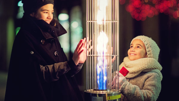 Girls are warming their hands on the restaurant gas heater in the cold winter night